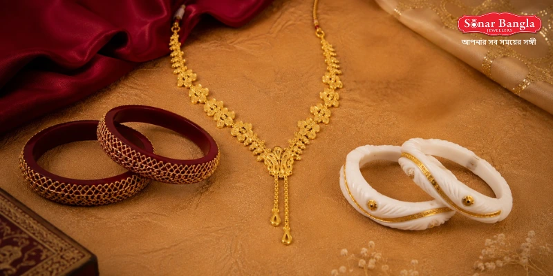 Pair of traditional sankha pola bangles crafted with detailed gold net work displayed alongside an elegant gold necklace.