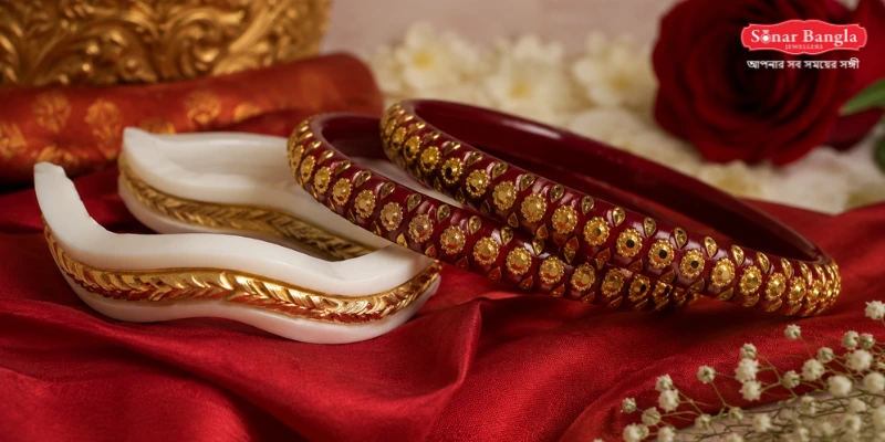 A classic pair of traditional sankha pola bangles detailed with precise floral and wave-patterned gold wirework on a red silk setting.